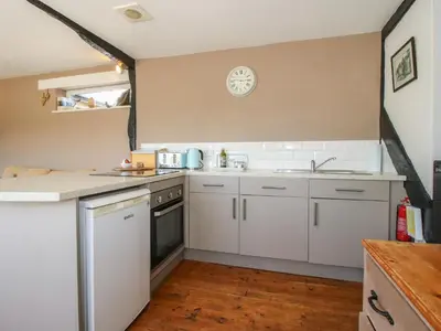 a kitchen with white cabinets and a clock on the wall at The Old Beams at Pont y Forwyn in Llansantffraid-ym-Mechain