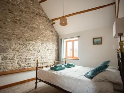 a bed in a room with a stone wall at 1 Beacon View Barn in Felindre