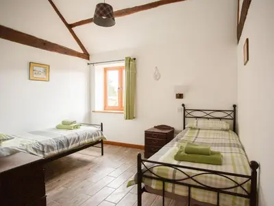 a bedroom with two beds and a window at 1 Beacon View Barn in Felindre