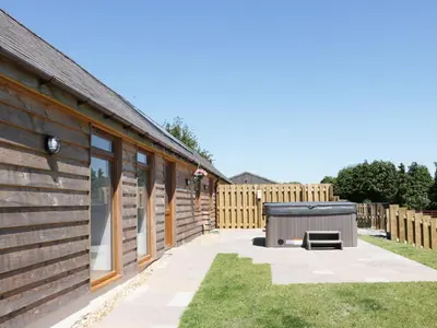 a backyard with a wooden house with a hot tub at 1 Beacon View Barn in Felindre