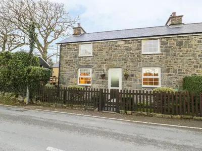 a stone house with a fence in front of it at Llwyn Celyn in Llanfachreth