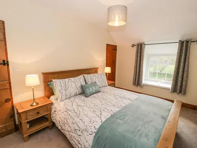 a bedroom with a large bed and a window at Llwyn Celyn in Llanfachreth