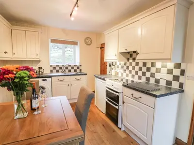 a kitchen with white cabinets and a wooden table at Llwyn Celyn in Llanfachreth