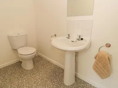 a white bathroom with a toilet and a sink at Awel Y Llan in Llanfair