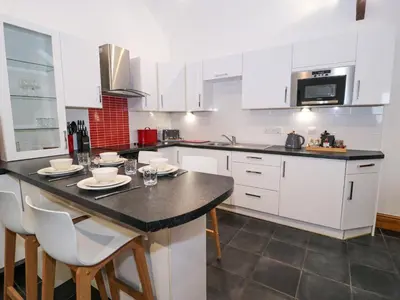 a kitchen with white cabinets and a black counter top at Cornel Glyd in Dyffryn