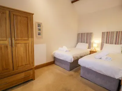 a bedroom with two beds and a cabinet in it at Sisial-y-Mor in Dyffryn