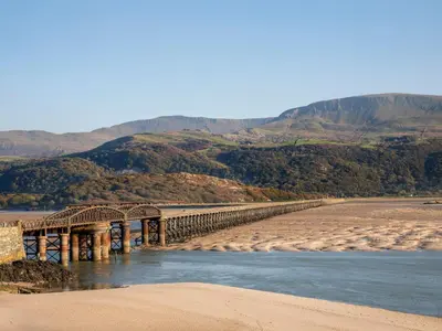 a bridge over a river with mountains in the background at Sisial-y-Mor in Dyffryn