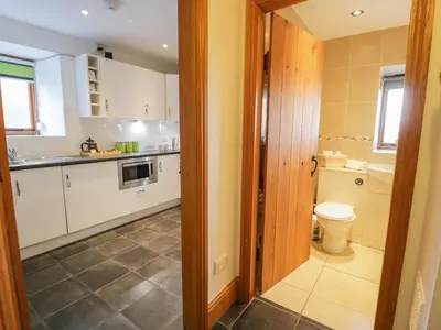 a kitchen with white cabinets and a toilet in a room at Sisial-y-Mor in Dyffryn
