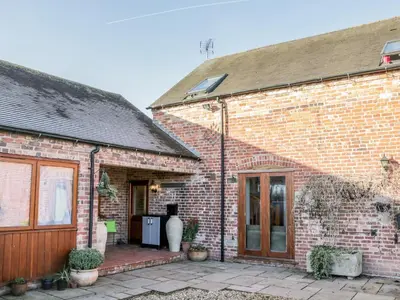 a brick house with a patio in front of it at Clun Forest Cottage in Monkhopton