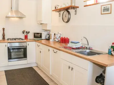 a kitchen with white cabinets and a sink at Clun Forest Cottage in Monkhopton