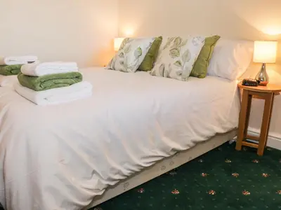 a bedroom with a white bed with towels on it at Clun Forest Cottage in Monkhopton