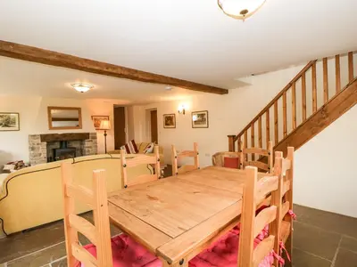 a dining room with a wooden table and a staircase at Timber Barn in Eardisland