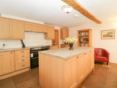 a kitchen with wooden cabinets and a vase of flowers on the counter at Timber Barn in Eardisland