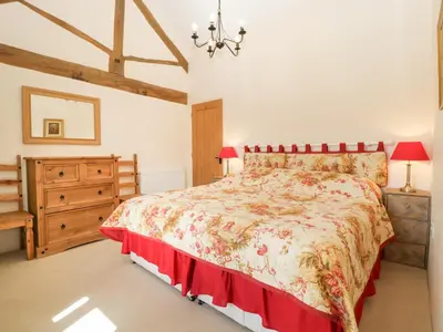 a bedroom with a large bed and a dresser at Timber Barn in Eardisland