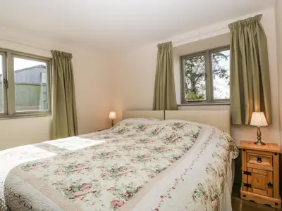 a bedroom with a bed and two windows at Timber Barn in Eardisland