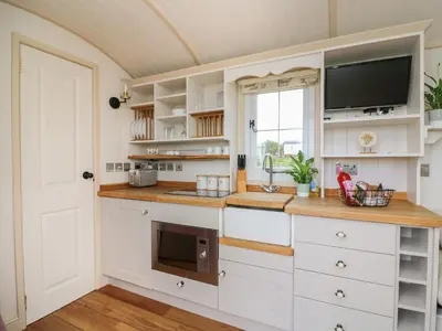 a kitchen with white cabinets and a flat screen tv at Shepherd's View in Saint Harmon