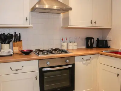 a kitchen with white cabinets and a stove top oven at Ryelands Cottage in Easthope