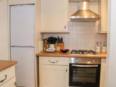 a kitchen with white cabinets and a stove top oven at Ryelands Cottage in Easthope