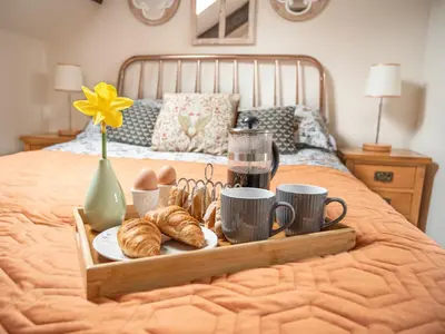 a tray of croissants and coffee cups on a bed at Coedmor Cottages in Lampeter