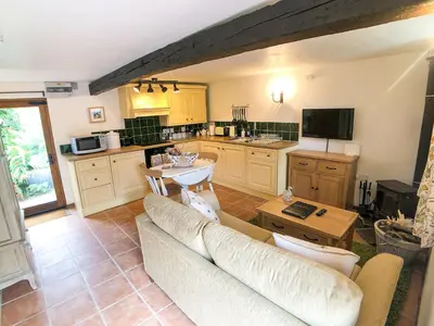 a living room with a couch and a kitchen at Coedmor Cottages in Lampeter