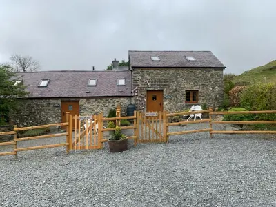 a house with a wooden gate and a fence at Tanyresgair Cottages in Aberystwyth