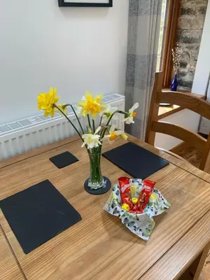a wooden table with a vase of flowers on it at Tanyresgair Cottages in Aberystwyth