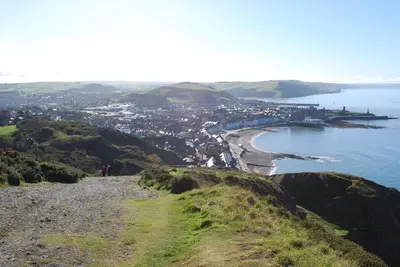 a view of a beach and the ocean from a hill at Tanyresgair Cottages in Aberystwyth