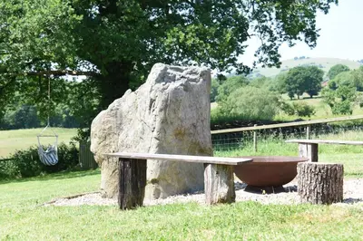 a stone bench sitting next to a large rock at Maen Llwyd in Llanyre