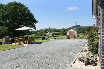 a gravel road with a table and an umbrella at Maen Llwyd in Llanyre
