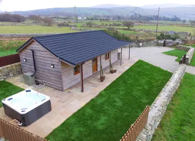 a small house with a hot tub in a yard at Enlli Lodge in Llanddwywe