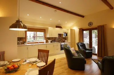 a kitchen and dining room with a table and chairs at Enlli Lodge in Llanddwywe