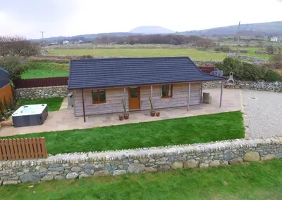 a small house with a stone wall and a yard at Enlli Lodge in Llanddwywe