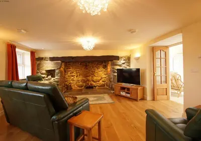 a living room with a couch and a stone fireplace at Hafod in Llanddwywe