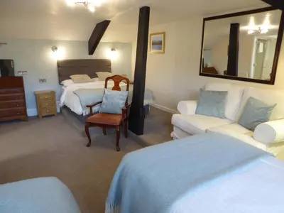 a bedroom with a bed and a couch and a mirror at The Grange Guest House in Brecon