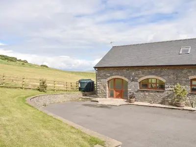 a stone house with a driveway next to a field at No 1 Pegraig Draw - Uk6434 in Llanychaiarn