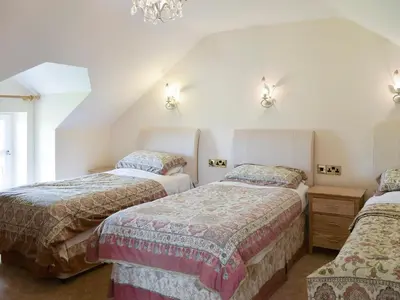 a bedroom with three beds and a chandelier at No 1 Pegraig Draw - Uk6434 in Llanychaiarn