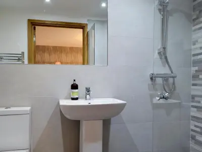 a white bathroom with a sink and a mirror at Maes Merlin in Llanddeusant