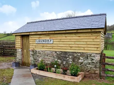 a wooden building with a sign that reads laundry at Maes Merlin in Llanddeusant