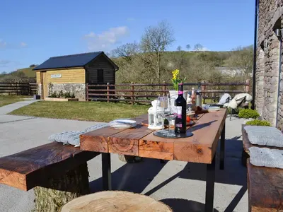 a wooden table with a bottle of wine on it at Maes Merlin in Llanddeusant