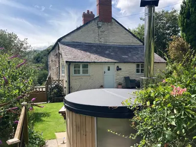 a house with a hot tub in a yard at Riverside Cottage in Llangollen