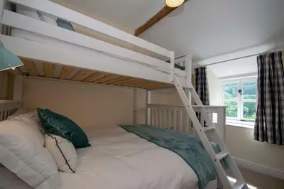 a bedroom with a bunk bed with a ladder at Riverside Cottage in Llangollen