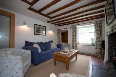a living room with a blue couch and a table at Riverside Cottage in Llangollen