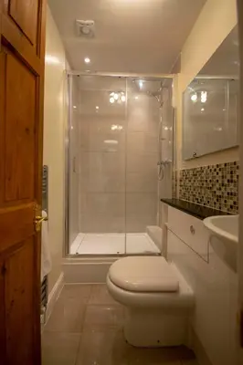 a bathroom with a shower and a toilet and a sink at Riverside Cottage in Llangollen