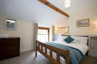 a bedroom with a bed and a dresser and a window at Riverside Cottage in Llangollen