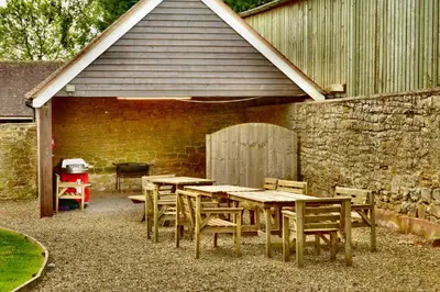 a group of tables and chairs in front of a brick wall at Upper Onibury Cottages in Onibury