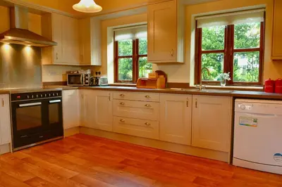 a kitchen with wooden floors and white cabinets at Upper Onibury Cottages in Onibury