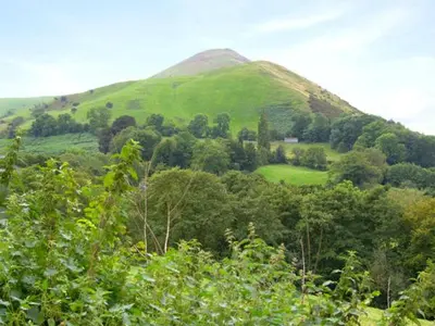 a green hill with a green field and trees at The Byre in Bishops Castle