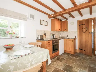 a kitchen with wooden cabinets and a table at The Old Workshop in Church Pulverbatch