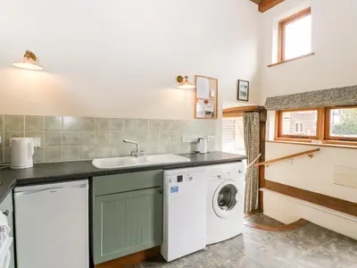 a laundry room with a sink and a washing machine at Stable End in Pembridge