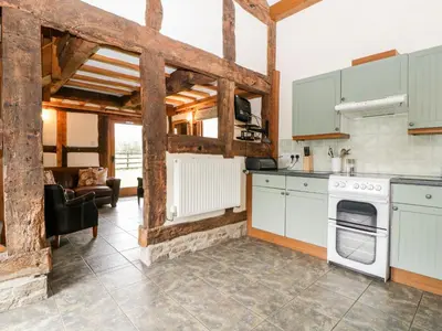 a kitchen with white appliances and a living room at Stable End in Pembridge